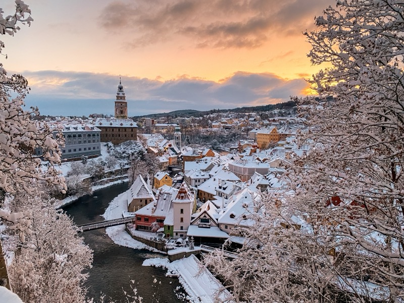 Český Krumlov, UNESCO. Historical town with Castle and Church at sunrise. Beautiful winter morning landscape with an illuminated monument. Snowy cityscape scene from the Cesky Krumlov, Czech Republic